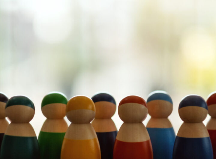 Group of wooden figurines in different colors standing in a row