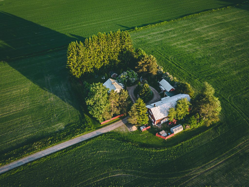 Aerial view of farmland with red barn and houses and harvest field in Finland