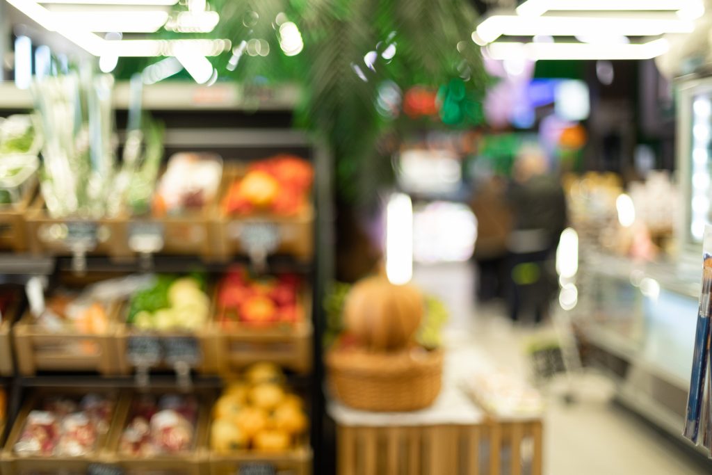 Blurred Supermarket Aisle Background Of Vegetables Department In Grocery Store