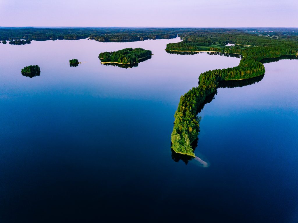Aerial view of blue lakes with islands and green forests  in Finland.