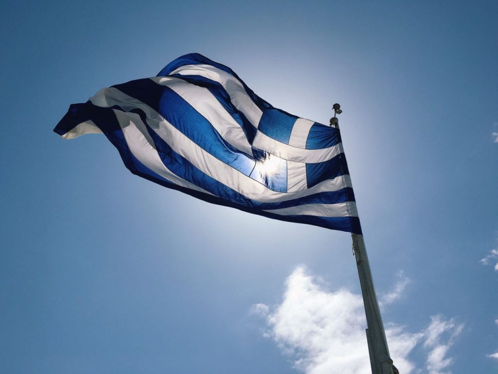 greek-flag-against-the-blue-sky-background-V4JV6ZX