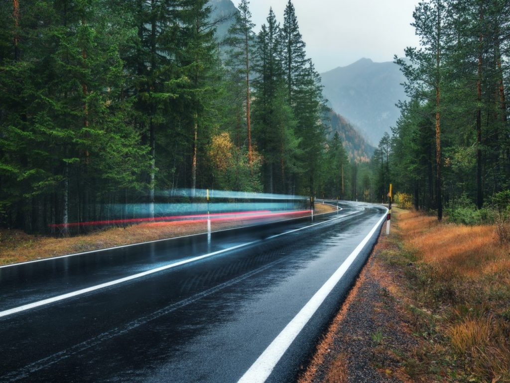 blurred-car-on-the-road-in-spring-forest-in-rain-6A3RPKN