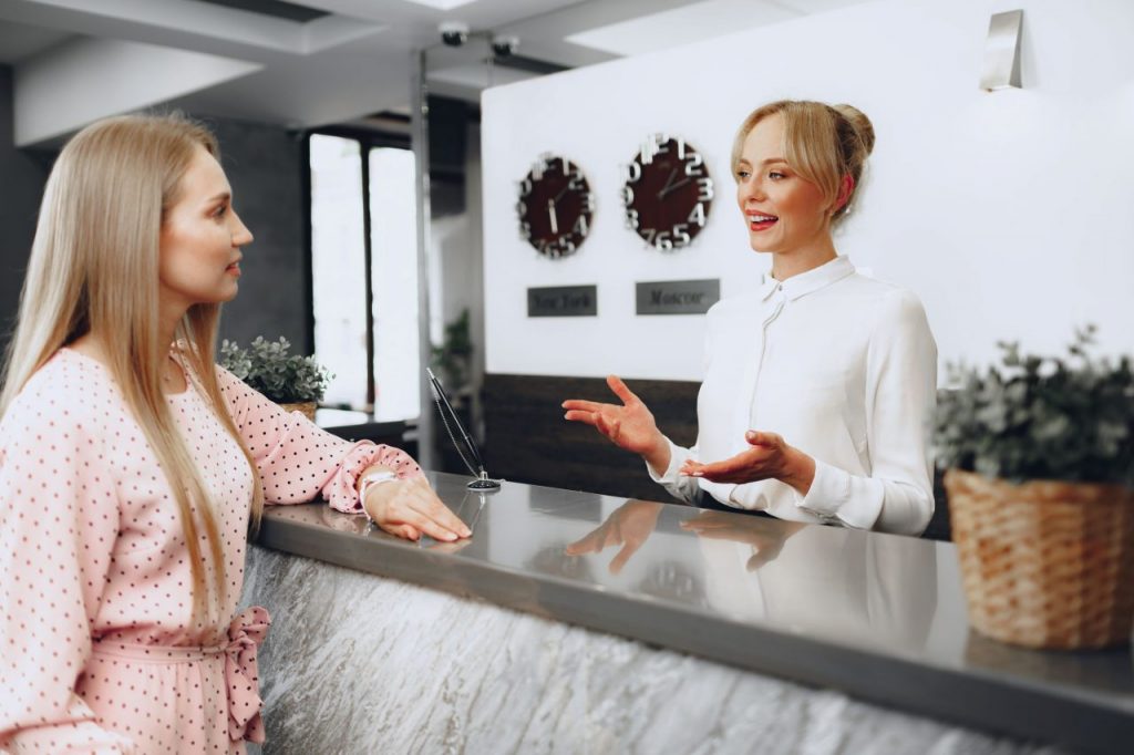blonde-woman-hotel-guest-checking-in-at-front-desk-XPXUXM7