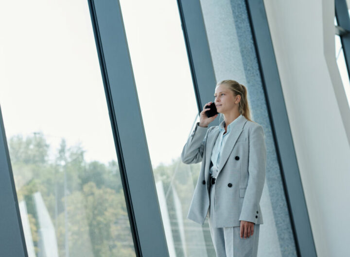 Young blond female agent or employee in formalwear talking on smartphone
